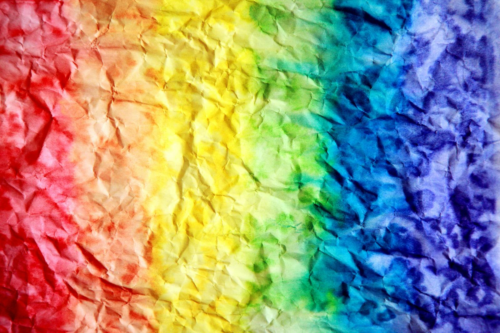 Bright and colorful rainbow gradient on crumpled paper texture, perfect for backgrounds.
